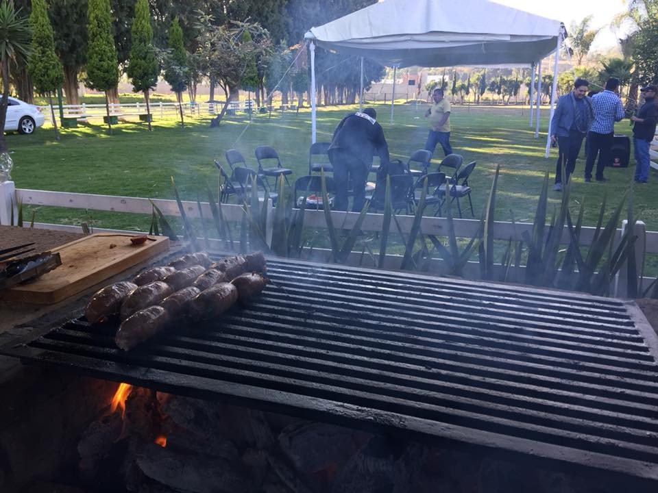 Parrillada con chorizo al carbón en el espacio Grill de Rancho San Antonio, con jardín y carpas al fondo en Zerezotla, Cholula