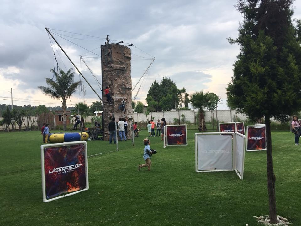 Muro de escalada y campo de Laser Tag instalados en el jardín para eventos infantiles y familiares en Rancho San Antonio