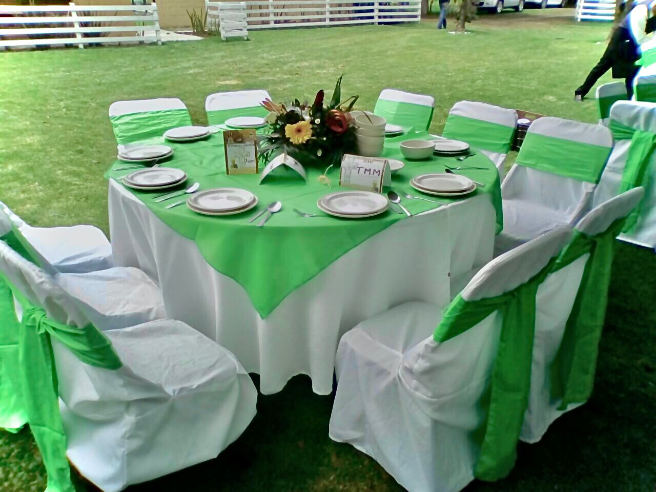 Mesa redonda decorada con mantel verde esmeralda y moños para evento social en el jardín de Cholula
