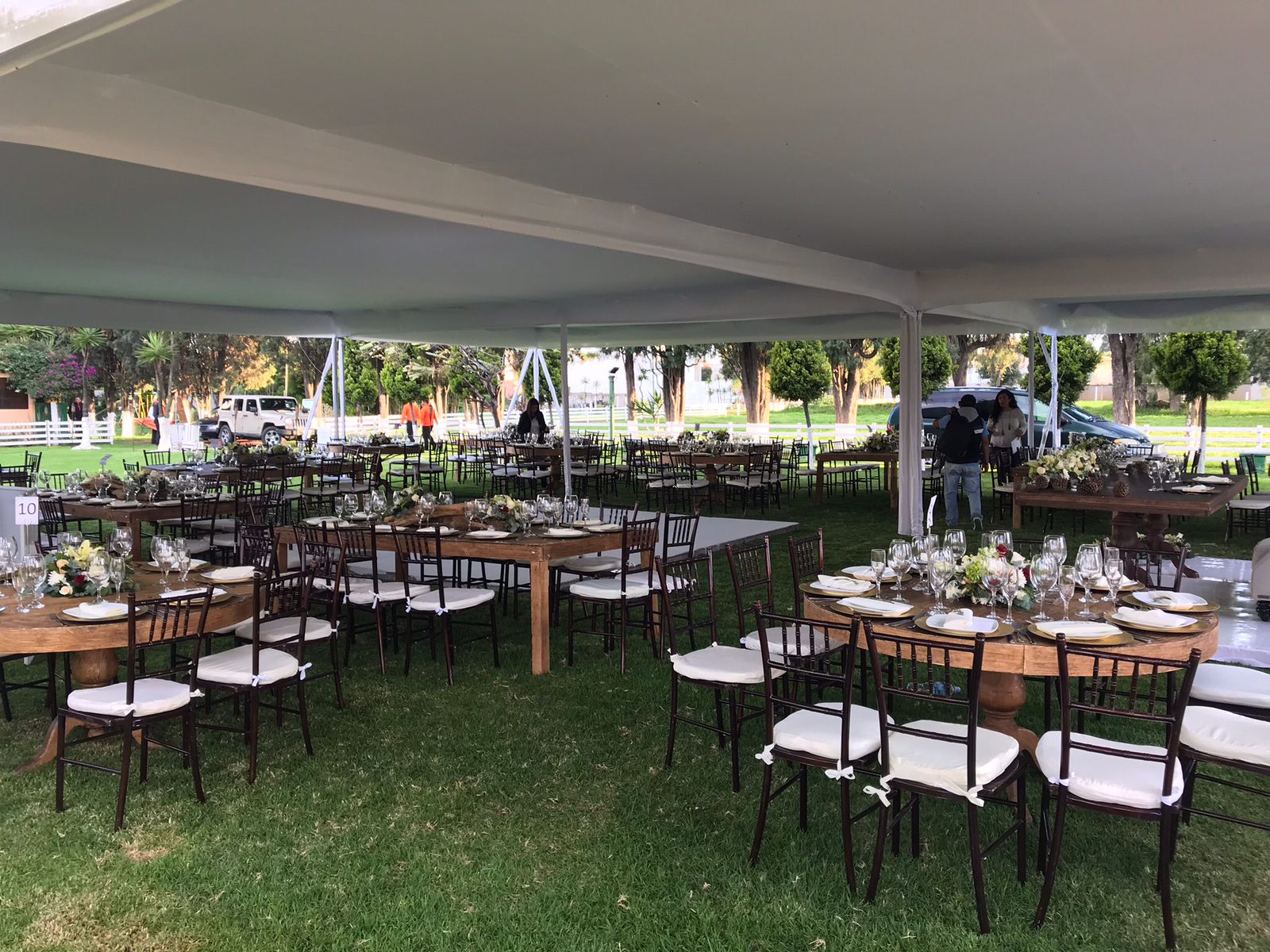 Interior del Salón de Trofeos con mesa rústica y platos de madera, vista al jardín a través del arco de ladrillo con caballo al fondo