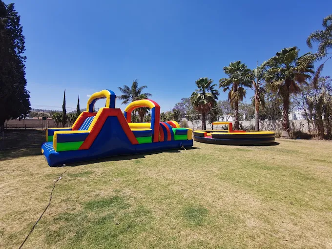 Circuito de obstáculos inflable con tobogán y cama elástica en el jardín de Rancho San Antonio para fiestas infantiles